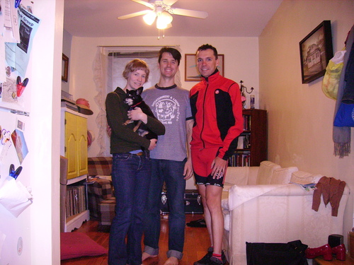 Tina avec un chien nois dans les bras, Phillip et Lino dans l’intérieur d’un appartement