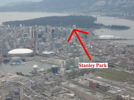 Vue aérienne de Vancouver. On y distingue la ville en gris au premier plan et le Stanley Park en vert foncé à l'arrière.