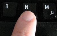 Un doigt posé sur la touche “n” sur un clavier